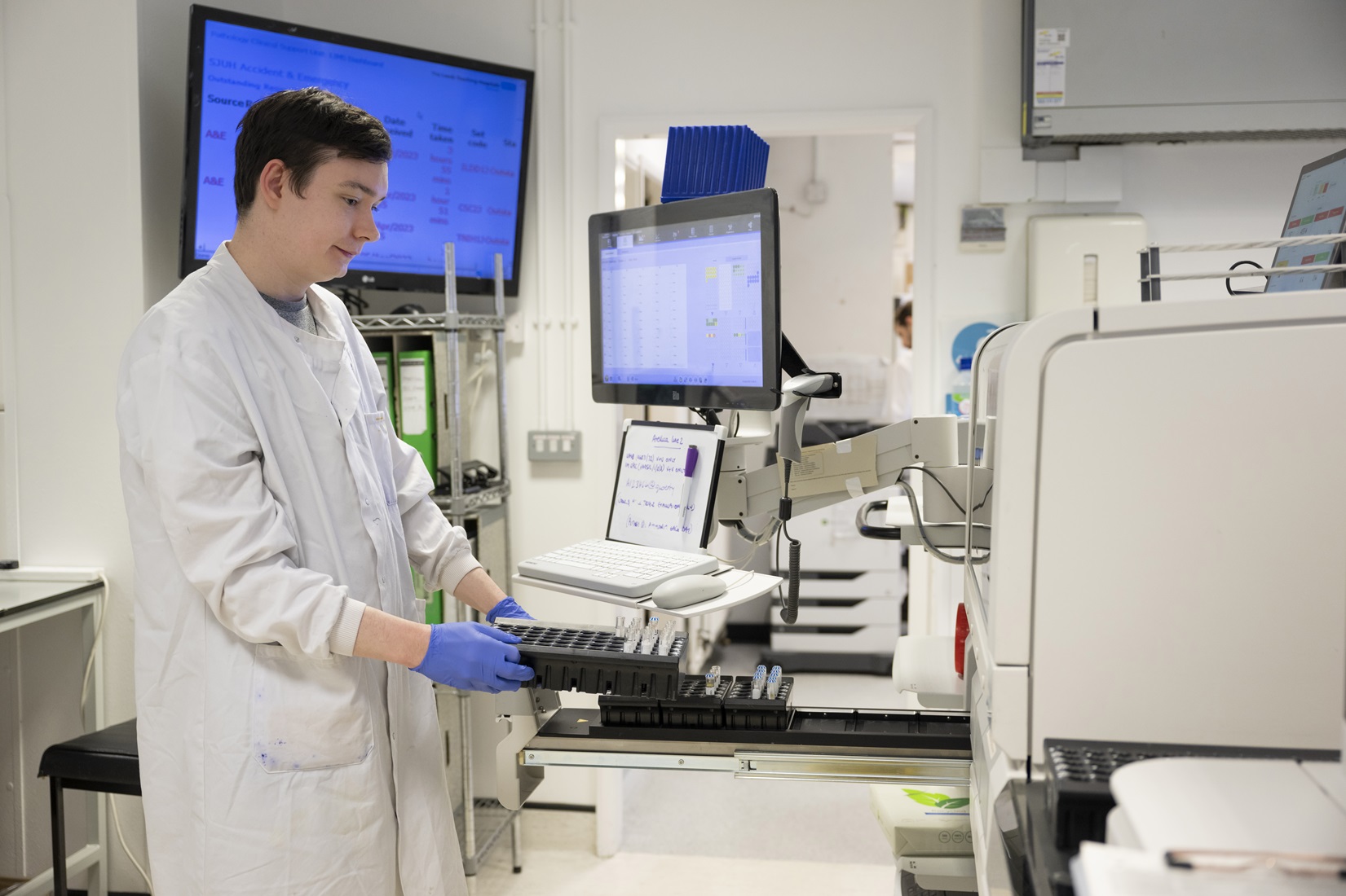 Pathologist with test tubes at computer terminal