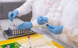 2 people in white lab coats sorting virology sample tubes