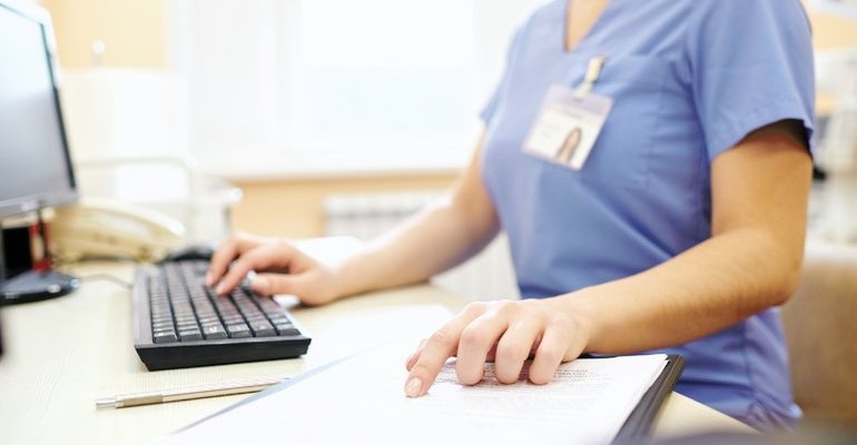 Person in scrubs working at desktop computer