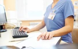 Person in scrubs working at desktop computer